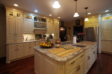 Eat-in kitchen - traditional medium tone wood floor and brown floor eat-in kitchen idea in Huntington with an undermount sink, raised-panel cabinets, white cabinets, granite countertops, beige backsplash, travertine backsplash, stainless steel appliances and an island