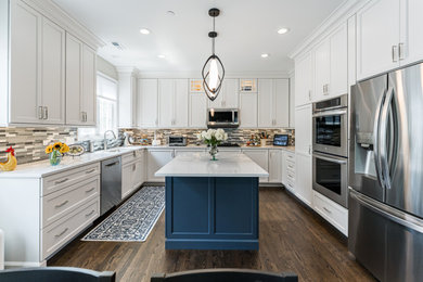 Open concept kitchen - mid-sized transitional medium tone wood floor open concept kitchen idea in Chicago with a drop-in sink, shaker cabinets, quartz countertops, multicolored backsplash, mosaic tile backsplash, stainless steel appliances, an island and white countertops