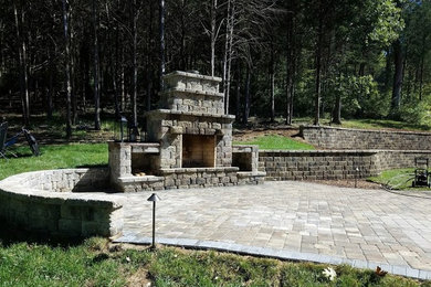 This is an example of a large full sun backyard concrete paver landscaping in Nashville with a fireplace.