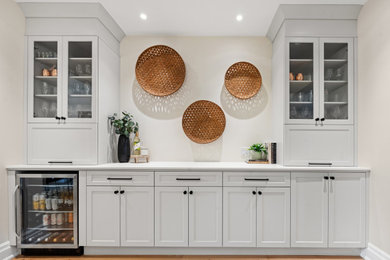 Example of a mid-sized classic l-shaped light wood floor and beige floor dry bar design in Ottawa with an undermount sink, shaker cabinets, white cabinets, quartz countertops, white backsplash, quartz backsplash and white countertops