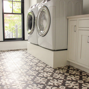 他の地域の大きいトラディショナルスタイルのおしゃれな洗濯室 (アンダーカウンターシンク、落し込みパネル扉のキャビネット、白いキャビネット、クオーツストーンカウンター、白い壁、セラミックタイルの床、左右配置の洗濯機・乾燥機、茶色い床) の写真