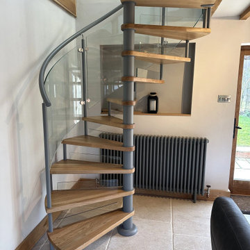 Lovely cottage spiral staircase with oak treads and curved glass railing