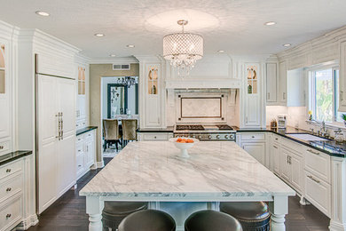Inspiration for a large arts and crafts u-shaped open plan kitchen in Orange County with an undermount sink, raised-panel cabinets, white cabinets, marble benchtops, white splashback, ceramic splashback, stainless steel appliances and with island.