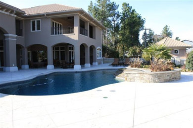 Hot tub - large coastal backyard stamped concrete and custom-shaped natural hot tub idea in Other