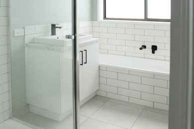 Small modern bathroom in Other with white cabinets, a drop-in tub, a corner shower, white tile, ceramic tile, green walls, ceramic floors, laminate benchtops, grey floor, a hinged shower door, grey benchtops and a single vanity.