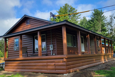 This is an example of a medium sized rustic bungalow house exterior in Providence with metal cladding, a pitched roof, a metal roof and shiplap cladding.