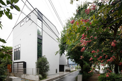 Idée de décoration pour une façade de maison grise urbaine à deux étages et plus avec un toit en appentis et un toit en métal.