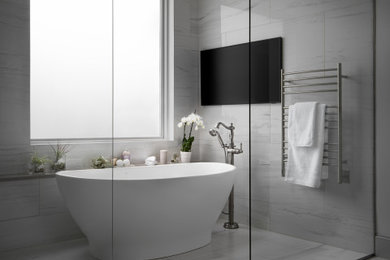 Идея дизайна: большая главная ванная комната в стиле неоклассика (современная классика) с отдельно стоящей ванной, душем над ванной, серой плиткой, керамогранитной плиткой, серыми стенами, полом из керамогранита, серым полом, открытым душем и сиденьем для душа