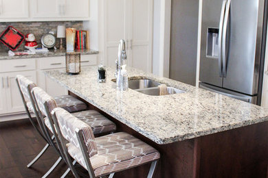 Kitchen - transitional brown floor kitchen idea in Chicago with white cabinets, granite countertops, beige backsplash, stainless steel appliances, an island and white countertops