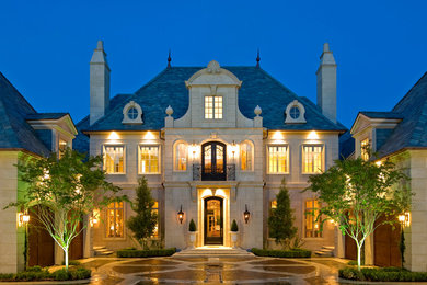Photo of a traditional two-storey beige exterior in Dallas with stone veneer and a hip roof.