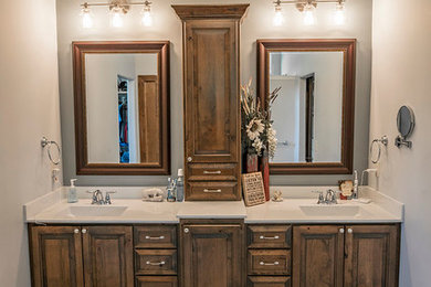Example of a mid-sized mountain style master ceramic tile and beige floor bathroom design in Wichita with raised-panel cabinets, brown cabinets, gray walls and onyx countertops