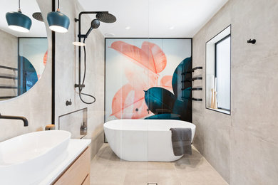 Design ideas for a contemporary master bathroom in Auckland with flat-panel cabinets, light wood cabinets, a freestanding tub, an open shower, gray tile, cement tile, grey walls, a vessel sink, beige floor, an open shower and white benchtops.