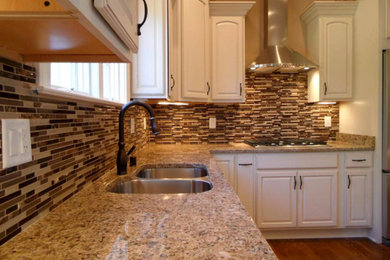 Example of a mid-sized transitional l-shaped dark wood floor and brown floor enclosed kitchen design in Milwaukee with an undermount sink, raised-panel cabinets, beige cabinets, granite countertops, multicolored backsplash, matchstick tile backsplash, stainless steel appliances and an island