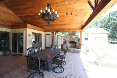 Imagen de patio clásico renovado grande en patio trasero con chimenea, suelo de hormigón estampado y toldo