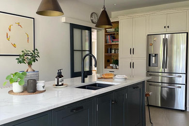 Photo of a large classic open plan kitchen in Belfast with an integrated sink, shaker cabinets, beige cabinets, quartz worktops, engineered quartz splashback, integrated appliances, porcelain flooring and an island.