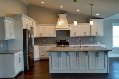 Open concept kitchen - large transitional l-shaped dark wood floor open concept kitchen idea in Other with an undermount sink, shaker cabinets, white cabinets, granite countertops, gray backsplash, porcelain backsplash, stainless steel appliances and an island