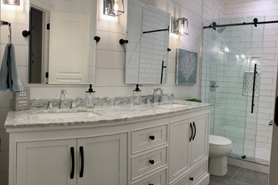 サクラメントにある高級な中くらいなトランジショナルスタイルのおしゃれな浴室 (家具調キャビネット、白いキャビネット、アルコーブ型シャワー、白いタイル、セラミックタイル、白い壁、セラミックタイルの床、アンダーカウンター洗面器、大理石の洗面台、グレーの床、引戸のシャワー、グレーの洗面カウンター、シャワーベンチ、洗面台2つ、独立型洗面台、塗装板張りの壁) の写真