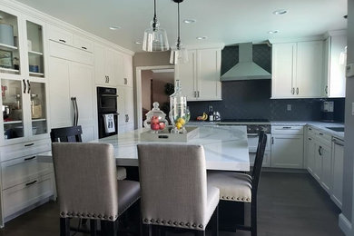 Large transitional u-shaped dark wood floor and brown floor enclosed kitchen photo in San Francisco with an undermount sink, shaker cabinets, white cabinets, quartzite countertops, gray backsplash, ceramic backsplash, paneled appliances, an island and white countertops
