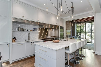 Contemporary kitchen in Chicago with an undermount sink, white cabinets, marble benchtops, stone slab splashback, stainless steel appliances and medium hardwood floors.