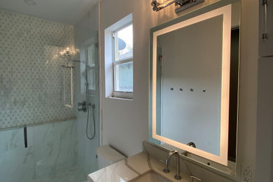 Example of a small transitional master white tile marble floor, white floor and single-sink walk-in shower design in Miami with shaker cabinets, white cabinets, a two-piece toilet, white walls, an undermount sink, solid surface countertops, a hinged shower door, white countertops and a built-in vanity