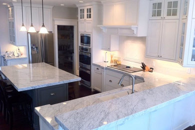 Mid-sized transitional u-shaped dark wood floor kitchen photo in Other with a double-bowl sink, recessed-panel cabinets, white cabinets, marble countertops, white backsplash, porcelain backsplash, stainless steel appliances and an island