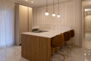 Diseño de cocina lineal y beige y blanca clásica renovada de tamaño medio abierta con fregadero bajoencimera, armarios con paneles lisos, puertas de armario beige, encimera de granito, electrodomésticos de acero inoxidable, suelo de mármol, una isla, suelo blanco y encimeras blancas