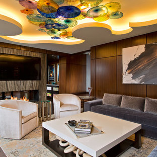 Photo of an expansive contemporary fully buried basement in Boston with brown walls, dark hardwood flooring, a two-sided fireplace, a stone fireplace surround and brown floors.