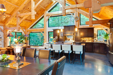 Large arts and crafts single-wall concrete floor eat-in kitchen photo in Vancouver with raised-panel cabinets, dark wood cabinets, granite countertops, stainless steel appliances and an island