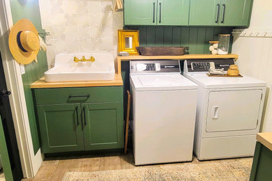 Inspiration for a small transitional shiplap wall utility room remodel in Phoenix with a farmhouse sink, green cabinets, white backsplash, porcelain backsplash and a side-by-side washer/dryer