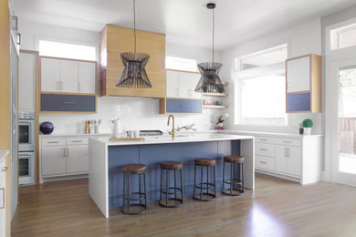 Inspiration for a contemporary u-shaped light wood floor and brown floor eat-in kitchen remodel in Dallas with an undermount sink, flat-panel cabinets, quartz countertops, white backsplash, subway tile backsplash, stainless steel appliances, an island and white countertops