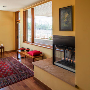Mittelgroßes, Repräsentatives, Fernseherloses, Abgetrenntes Mediterranes Wohnzimmer mit gelber Wandfarbe, hellem Holzboden, Eckkamin, Kaminsims aus Metall und beigem Boden in Albuquerque