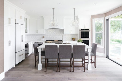 Inspiration for a traditional l-shaped kitchen in Orange County with an undermount sink, shaker cabinets, white cabinets, multi-coloured splashback, panelled appliances, light hardwood floors and with island.
