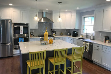 Example of a trendy brown floor kitchen design in New York with an undermount sink, shaker cabinets, white cabinets, stainless steel appliances and an island