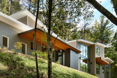 Mid-sized contemporary two-storey grey house exterior in Other with concrete fiberboard siding, a shed roof and a metal roof.