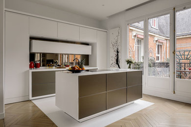 Photo of an expansive contemporary open plan kitchen in Paris with an undermount sink, flat-panel cabinets, white cabinets, mirror splashback, panelled appliances, light hardwood floors, with island and beige floor.