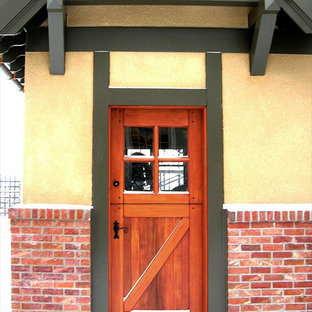 Idéer för att renovera en stor eklektisk ingång och ytterdörr, med gula väggar, tegelgolv, en tvådelad stalldörr och mellanmörk trädörr