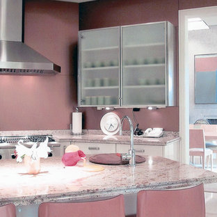 Aménagement d'une grande arrière-cuisine moderne en U avec un évier posé, un placard à porte vitrée, des portes de placard noires, un plan de travail en granite, une crédence rose, une crédence en feuille de verre, un électroménager en acier inoxydable, un sol en calcaire et un îlot central.