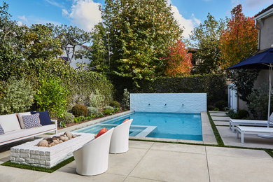 Inspiration for a mid-sized contemporary backyard rectangular pool in Orange County with a water feature and concrete pavers.