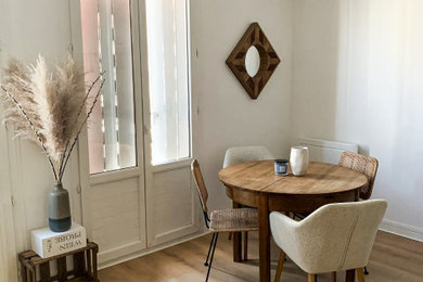 Cette image montre une salle à manger ouverte sur la cuisine minimaliste de taille moyenne avec un mur blanc, parquet clair, aucune cheminée, un sol marron et éclairage.