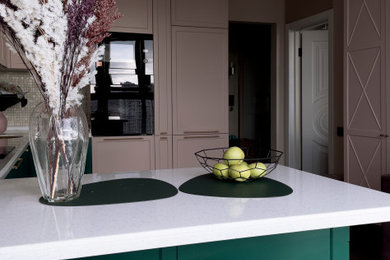 Стильный дизайн: отдельная, угловая кухня среднего размера в стиле неоклассика (современная классика) с врезной мойкой, фасадами с выступающей филенкой, зелеными фасадами, столешницей из акрилового камня, розовым фартуком, фартуком из плитки мозаики, черной техникой, полом из винила, полуостровом, коричневым полом, белой столешницей и двухцветным гарнитуром - последний тренд