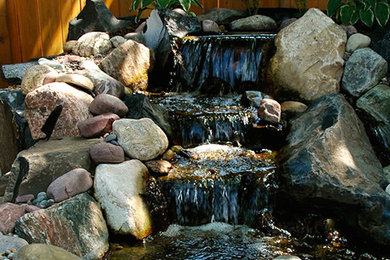 This is an example of a mid-sized traditional partial sun backyard pond in Calgary for summer.