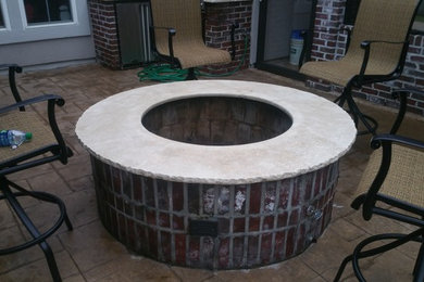 This is an example of a large rustic back patio in New Orleans with a fire feature, stamped concrete and no cover.
