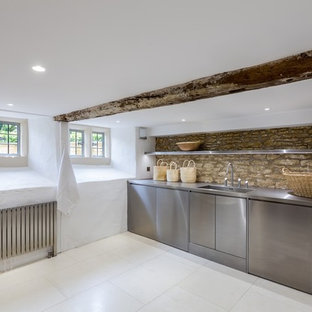 Ejemplo de lavadero contemporáneo con puertas de armario en acero inoxidable, encimera de acero inoxidable y suelo de piedra caliza