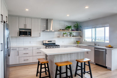 Example of a trendy brown floor eat-in kitchen design in Other with an undermount sink, flat-panel cabinets, white cabinets, quartz countertops, white backsplash, stainless steel appliances, an island and white countertops