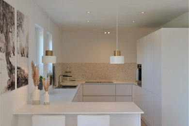 Contemporary kitchen in Munich with mosaic tiled splashback and white worktops.