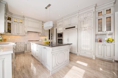 Eat-in kitchen - large transitional u-shaped travertine floor eat-in kitchen idea in Toronto with an undermount sink, raised-panel cabinets, distressed cabinets, quartzite countertops, beige backsplash, paneled appliances and an island