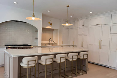 Large minimalist l-shaped light wood floor and beige floor eat-in kitchen photo in Los Angeles with an undermount sink, shaker cabinets, white cabinets, quartzite countertops, white backsplash, ceramic backsplash, stainless steel appliances, an island and white countertops