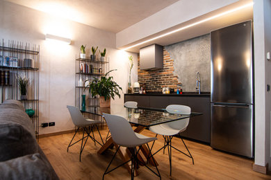Foto di una piccola sala da pranzo aperta verso il soggiorno industriale con pavimento in laminato e pareti in mattoni