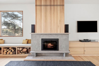 Photo of a large contemporary open concept family room in Geelong with white walls, light hardwood floors, a standard fireplace and a concrete fireplace surround.