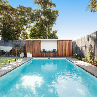 Photo of a large contemporary backyard rectangular pool in Melbourne with a pool house and natural stone pavers.